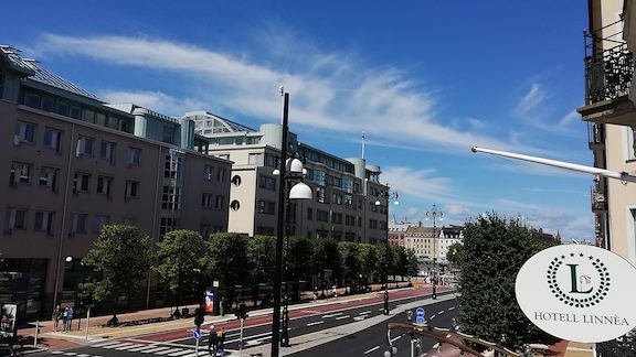 The main street, Järnvägsgatan, during a sunny day seen from a hotel room with the Hotell Linnéa sign visible.
