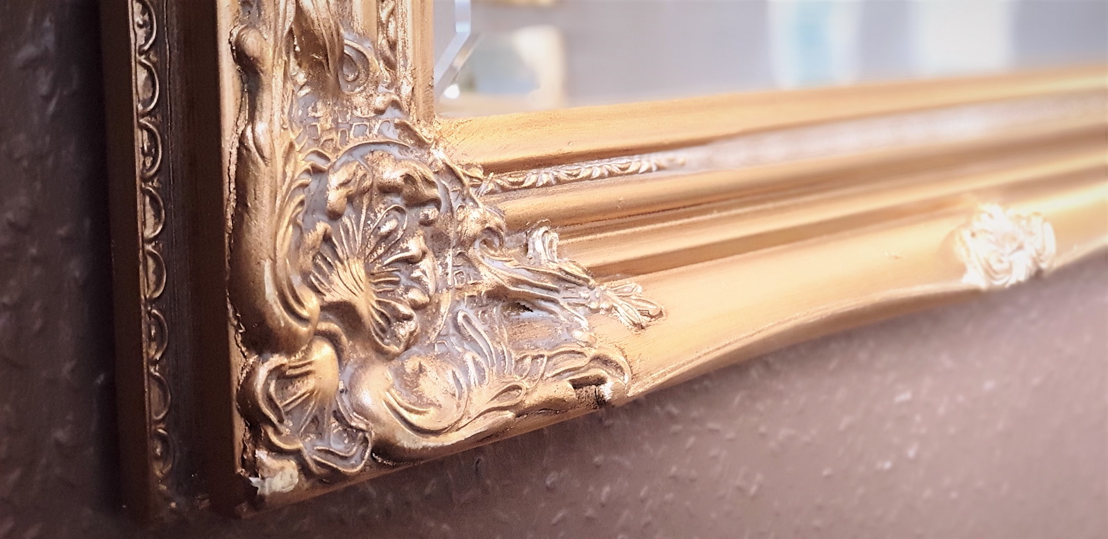 Close up of a mirror with a gold frame.