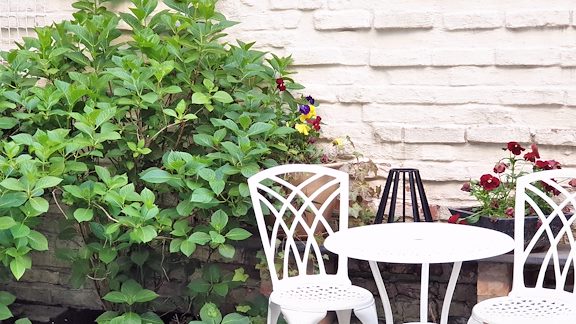 Two white chairs and a table in the hotel courtyard.