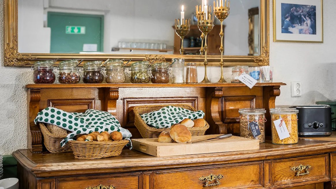 En stor träbyrå med olika typer av bröd, bullar, nötter och flingor ovanpå.