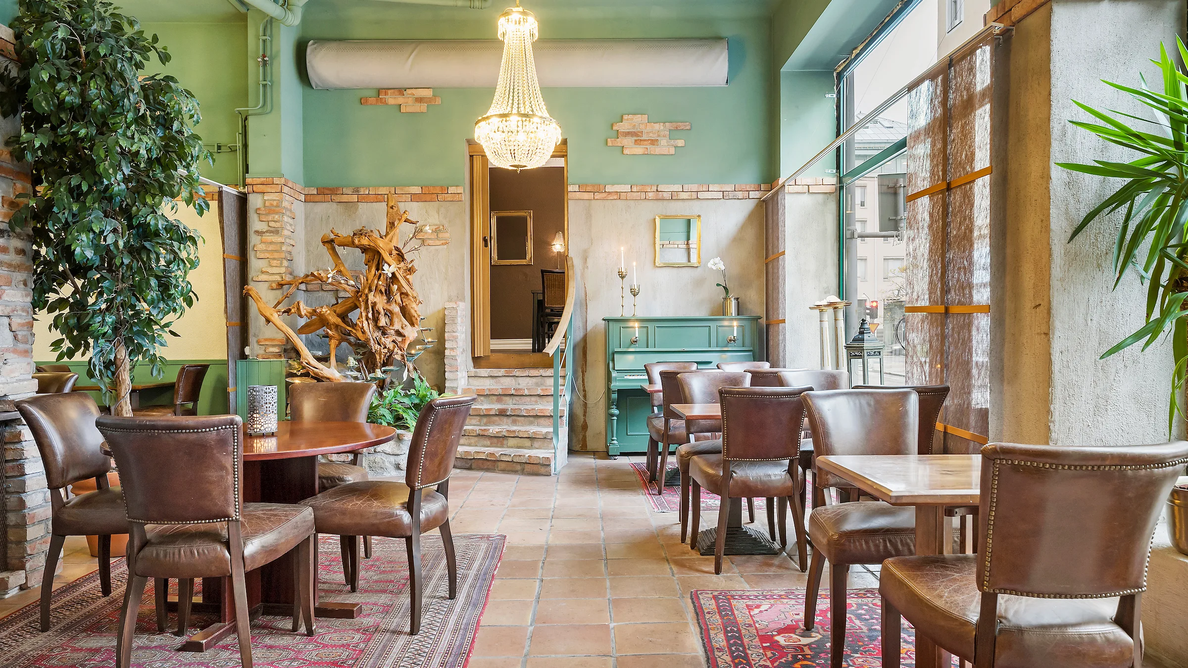 The hotel breakfast room. A bright room with tall ceilings, a chandelier, brown tables and chairs.
