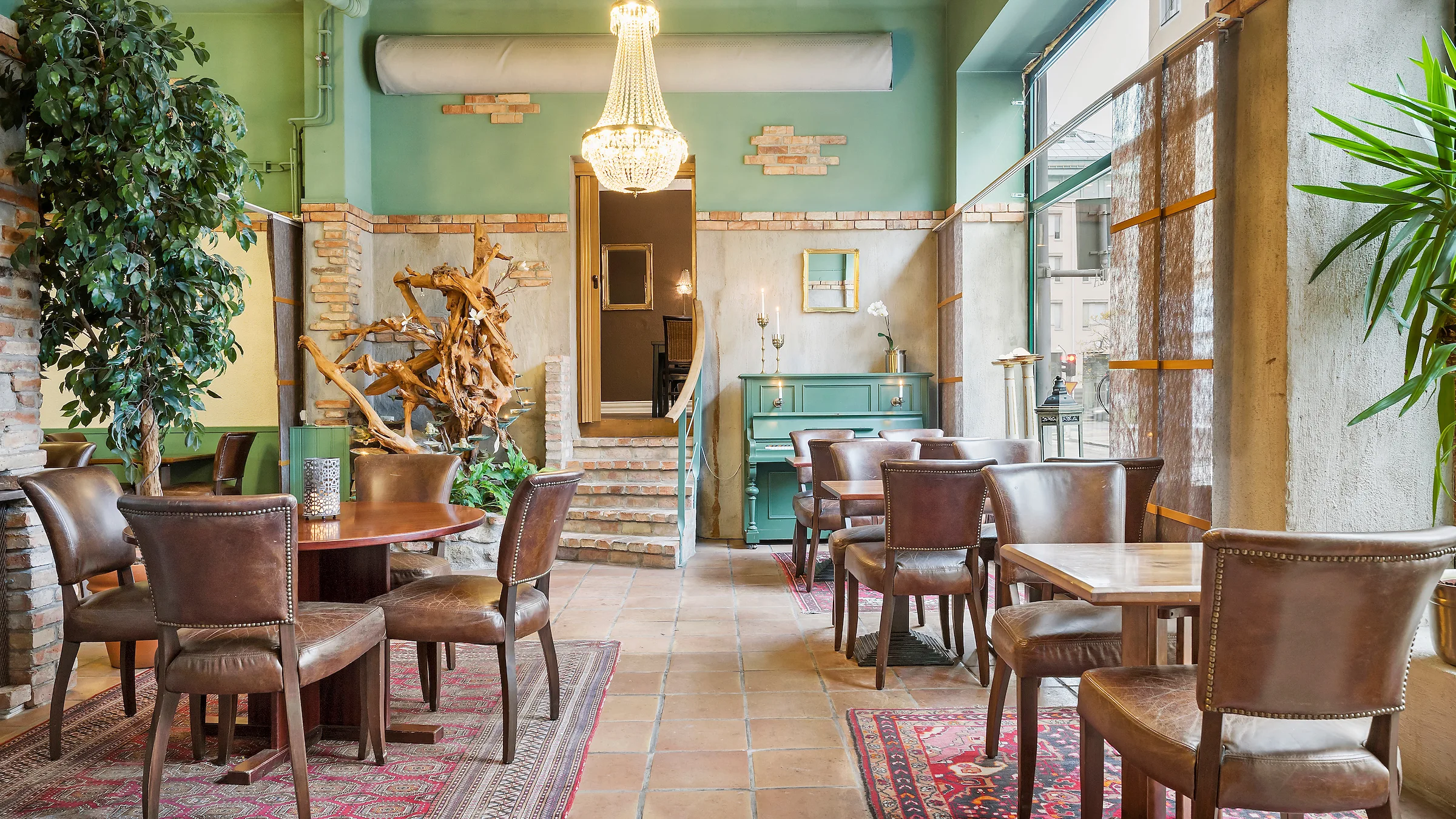 Hotell Linnéas frukostmatsal. Ett ljust rum med högt i tak, en kristallkrona, bruna bord och stolar.