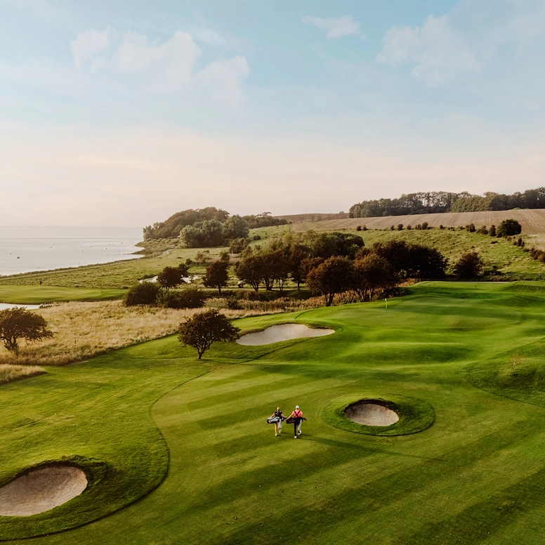 En golfbana längst med en kust under en blå himmel en solig dag.