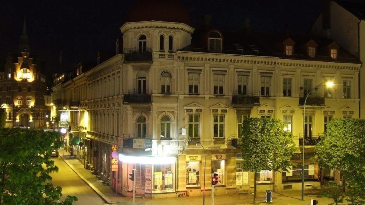 Hotell Linnéas vita hörnbyggnad på Järnvägsgatan under kvällstid, ett klassiskt hus från 1887.