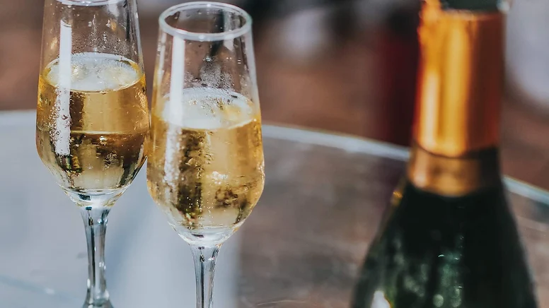 Två fyllda champagneglas och en flaska mousserande vin.